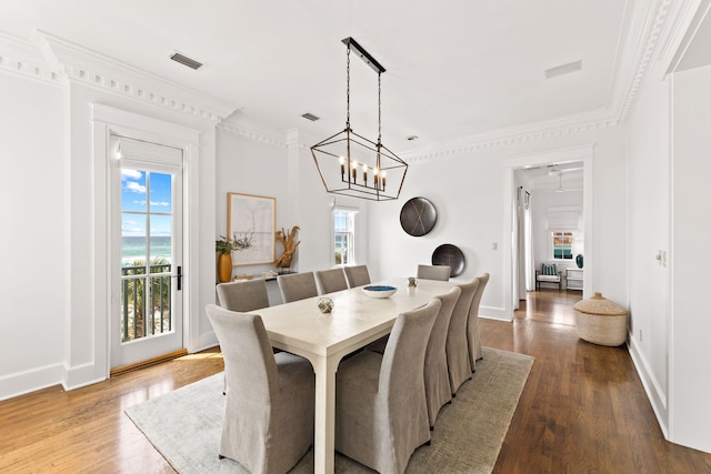 dining space featuring crown molding, light wood-type flooring, and a chandelier