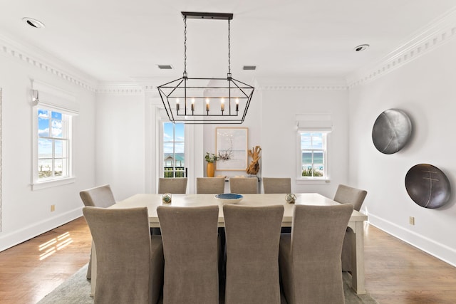 dining room featuring light wood finished floors, visible vents, ornamental molding, and a wealth of natural light