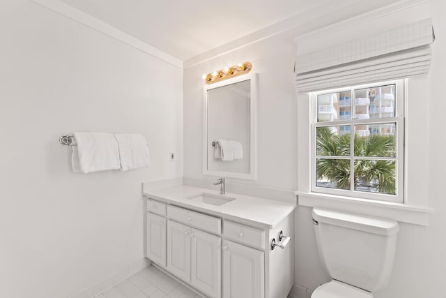 bathroom featuring toilet, vanity, baseboards, ornamental molding, and tile patterned floors