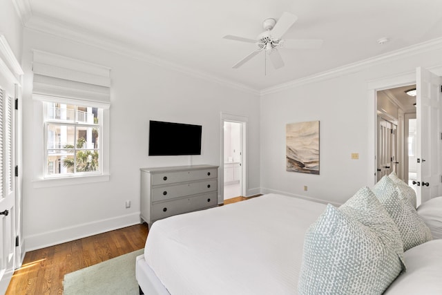 bedroom featuring ornamental molding, dark wood finished floors, baseboards, and ensuite bathroom