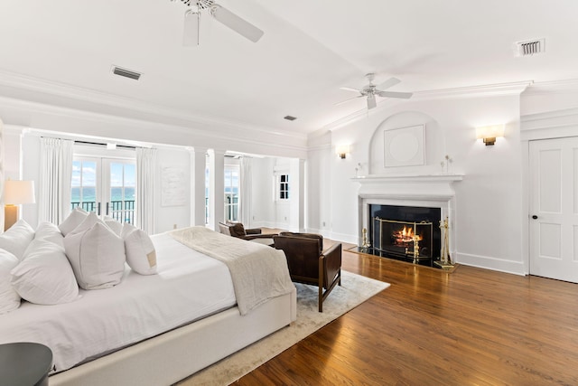 bedroom with a warm lit fireplace, access to outside, visible vents, and dark wood-type flooring