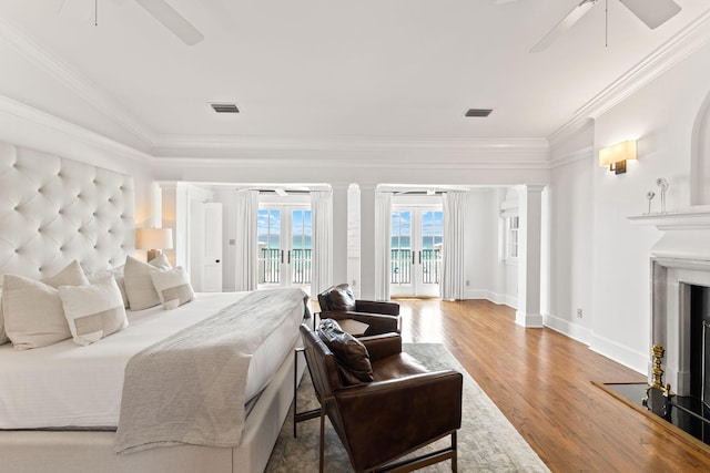 bedroom with light hardwood / wood-style flooring, ceiling fan, access to exterior, a fireplace, and ornamental molding