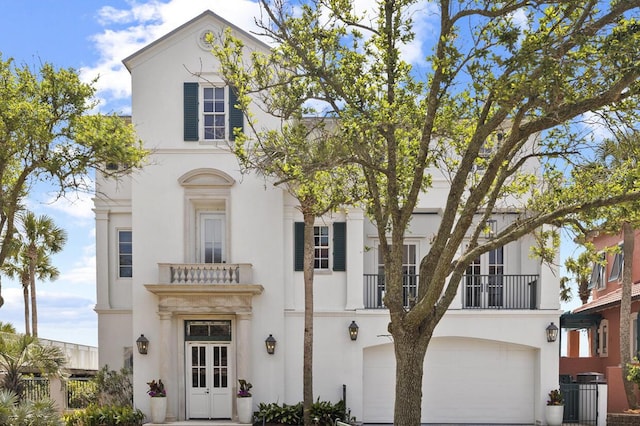 view of front of house featuring a garage, a balcony, central AC unit, and stucco siding