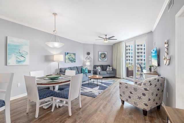 dining space featuring wood-type flooring, ornamental molding, expansive windows, and ceiling fan