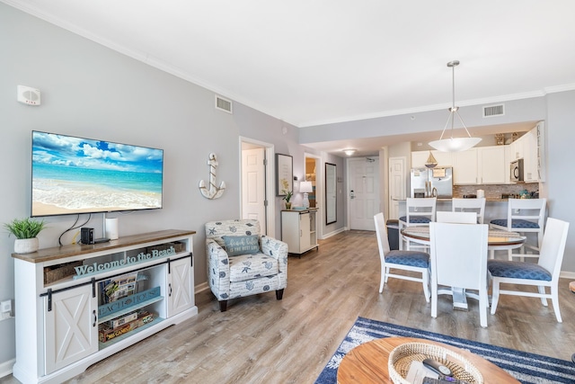 living room with ornamental molding and light hardwood / wood-style flooring