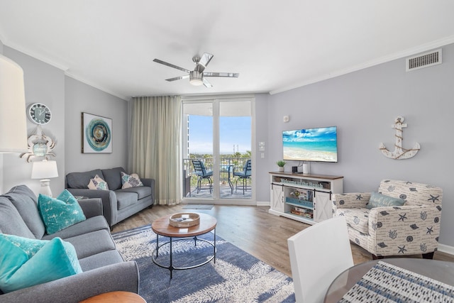 living room featuring wood-type flooring, ceiling fan, and crown molding