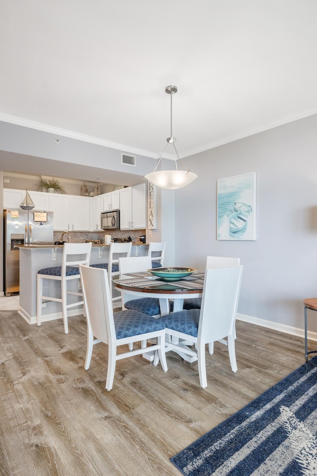 dining room featuring ornamental molding and light hardwood / wood-style flooring