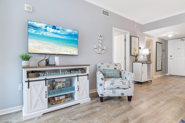 living area with crown molding and light hardwood / wood-style floors