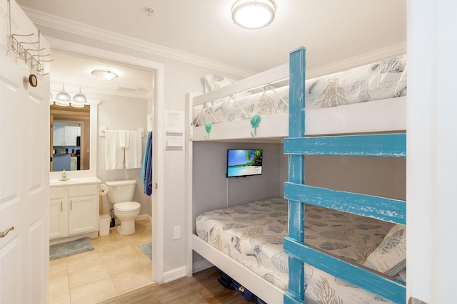 bedroom featuring ornamental molding, baseboards, connected bathroom, and a sink