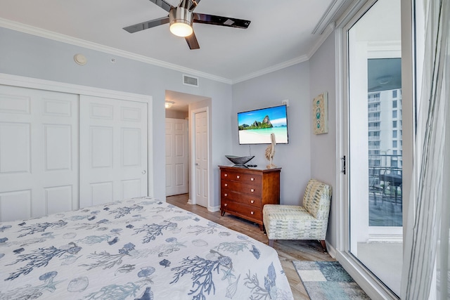 bedroom with ceiling fan, wood finished floors, visible vents, a closet, and crown molding