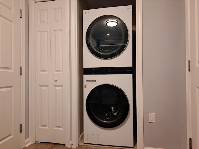 laundry room with stacked washer and dryer, light wood finished floors, and laundry area