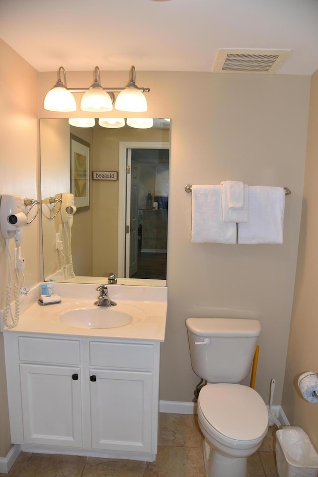 half bath featuring baseboards, visible vents, vanity, and toilet