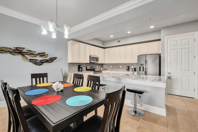 dining space with sink, crown molding, a notable chandelier, and light tile flooring