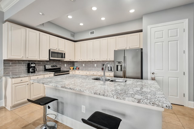 kitchen with sink, appliances with stainless steel finishes, light tile floors, and a breakfast bar area