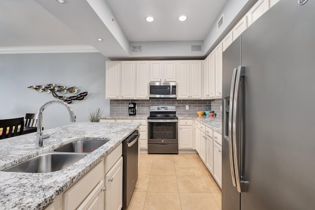 kitchen with light stone counters, appliances with stainless steel finishes, sink, light tile flooring, and ornamental molding