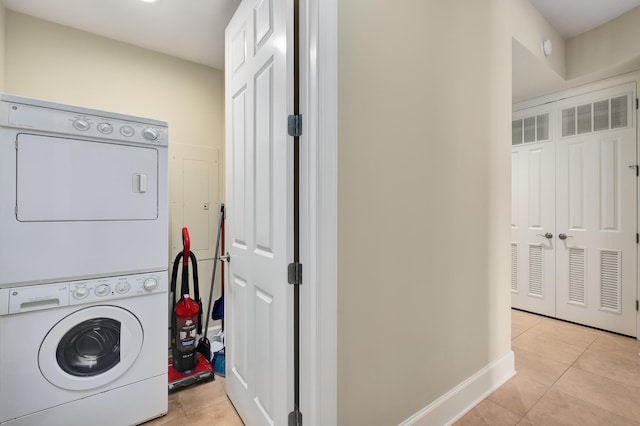 laundry room with stacked washer and dryer and light tile flooring