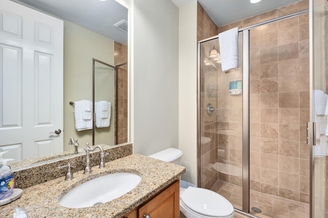 bathroom with vanity with extensive cabinet space, toilet, and a shower with shower door