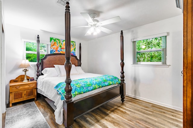 bedroom featuring hardwood / wood-style flooring, ceiling fan, and multiple windows