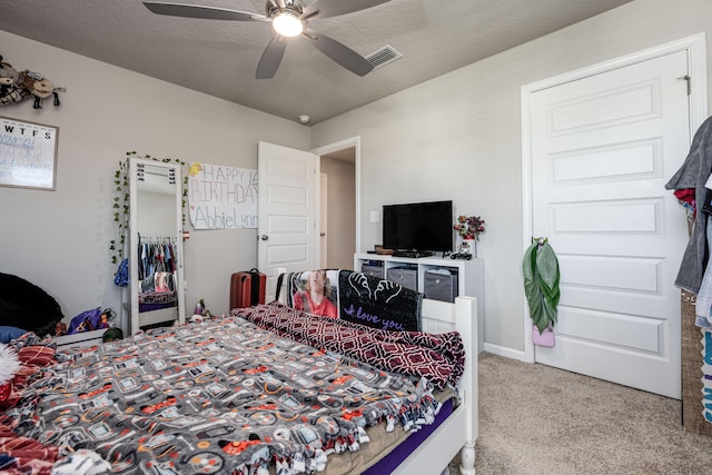 bedroom featuring ceiling fan, a textured ceiling, and carpet flooring