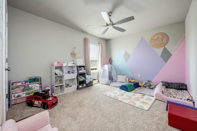 recreation room with carpet floors, a textured ceiling, and ceiling fan