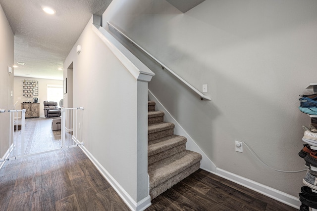 stairs with a textured ceiling and hardwood / wood-style flooring