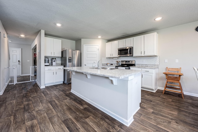 kitchen with white cabinets, appliances with stainless steel finishes, and dark hardwood / wood-style floors