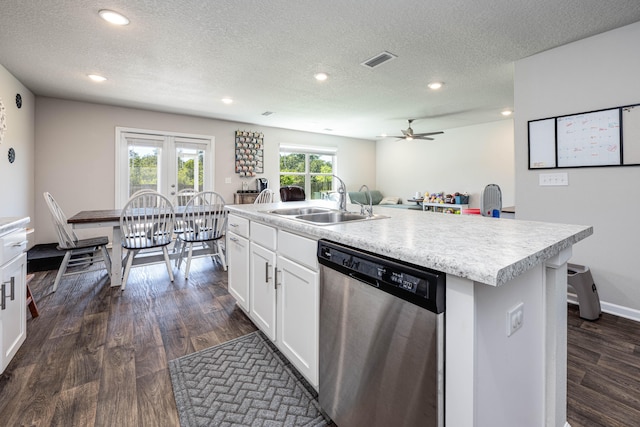 kitchen featuring white cabinets, an island with sink, sink, stainless steel dishwasher, and dark wood-type flooring