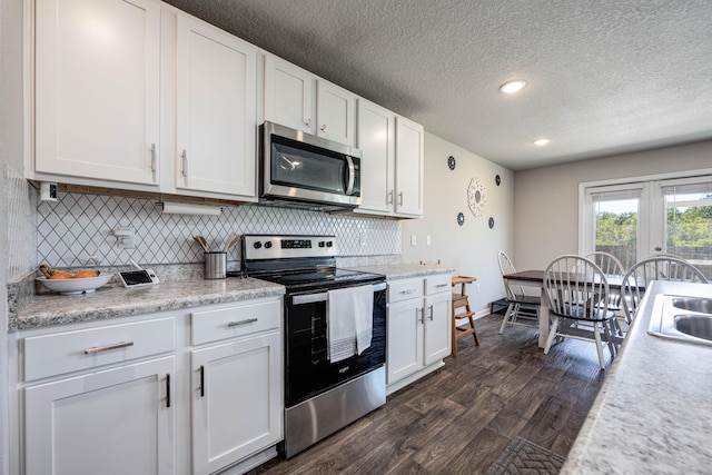 kitchen with appliances with stainless steel finishes, decorative backsplash, white cabinets, dark hardwood / wood-style flooring, and a textured ceiling