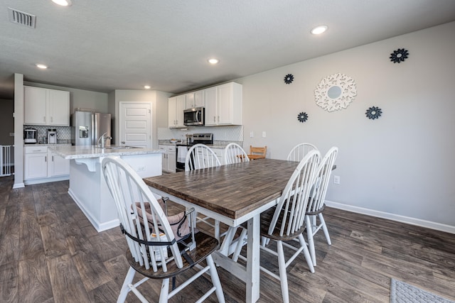 dining area featuring a textured ceiling, dark hardwood / wood-style flooring, and sink