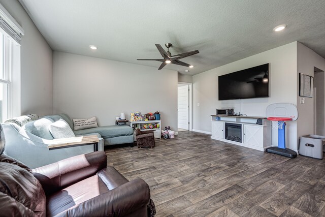 living room with ceiling fan, a textured ceiling, and dark wood-type flooring