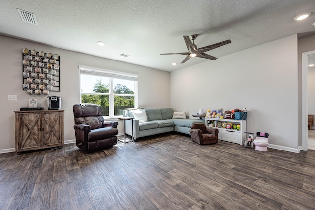 living room with ceiling fan, a textured ceiling, and dark wood-type flooring