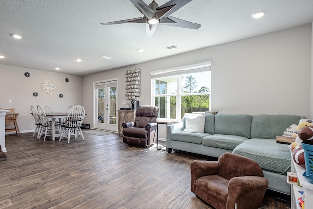 living room featuring ceiling fan, dark wood-type flooring, and a textured ceiling