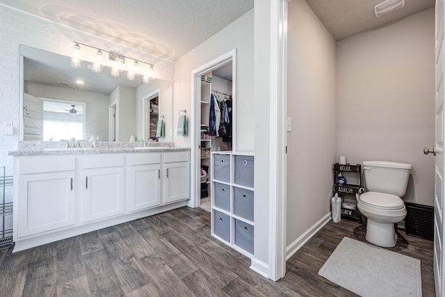 bathroom with a textured ceiling, hardwood / wood-style floors, vanity, and toilet