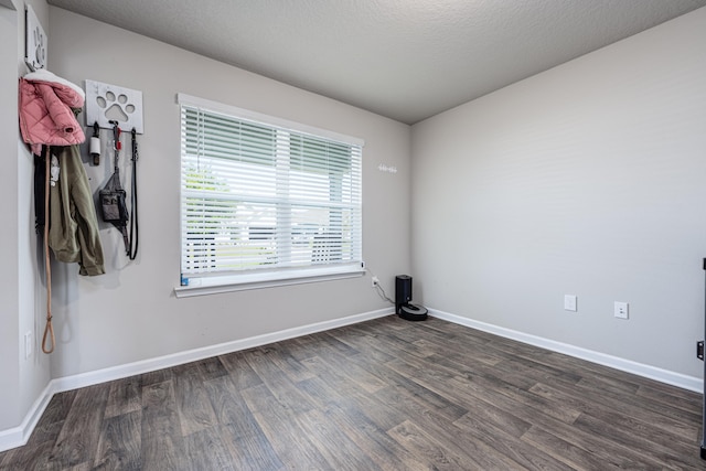 empty room with a textured ceiling and dark hardwood / wood-style floors