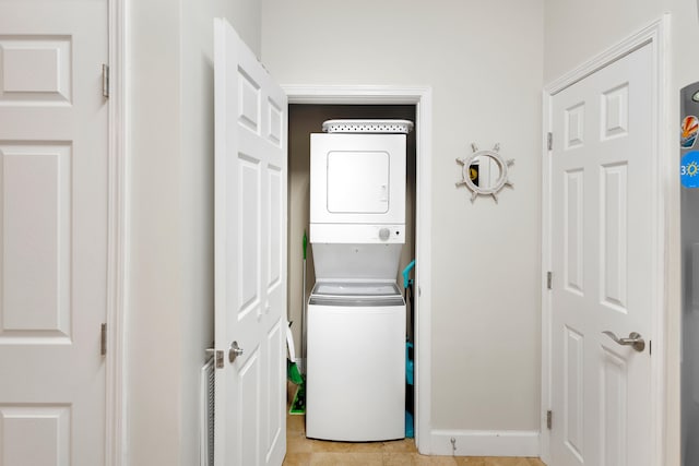 laundry area featuring stacked washer / dryer and light tile floors