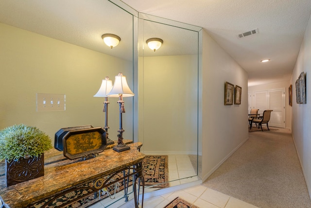 corridor featuring light colored carpet and a textured ceiling