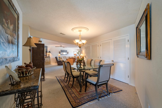 carpeted dining room featuring ceiling fan with notable chandelier and a textured ceiling