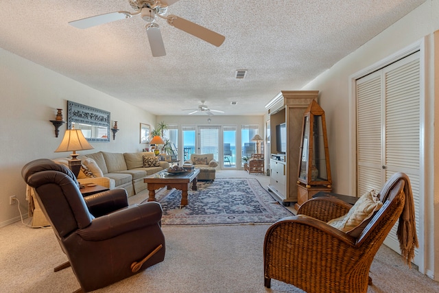 carpeted living room featuring a textured ceiling and ceiling fan