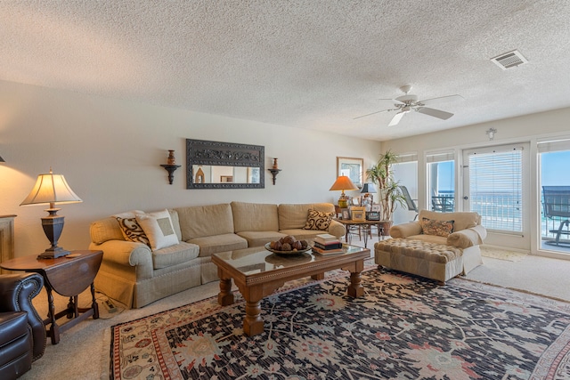 carpeted living room with ceiling fan and a textured ceiling