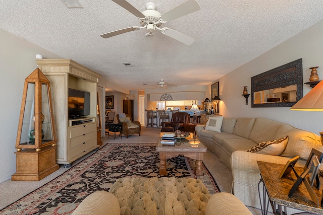 carpeted living room featuring ceiling fan and a textured ceiling