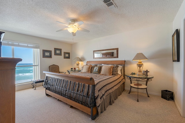 bedroom featuring light carpet, ceiling fan, and a textured ceiling