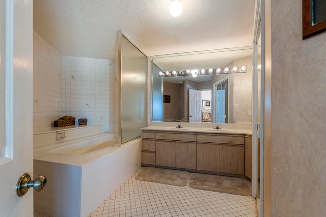 bathroom with a textured ceiling, oversized vanity, tile floors, and tiled shower / bath