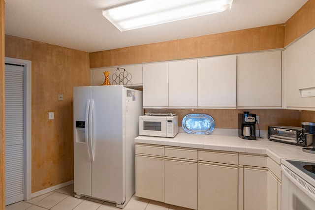 kitchen with white cabinetry, tile countertops, white appliances, and light tile floors