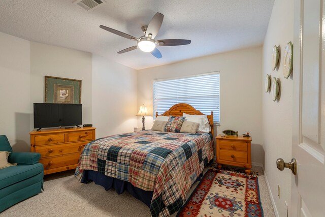 bedroom with a textured ceiling, ceiling fan, and carpet