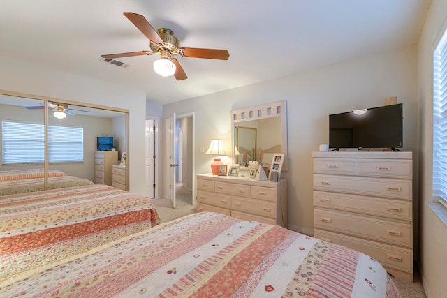 bedroom with a closet, ceiling fan, multiple windows, and carpet floors