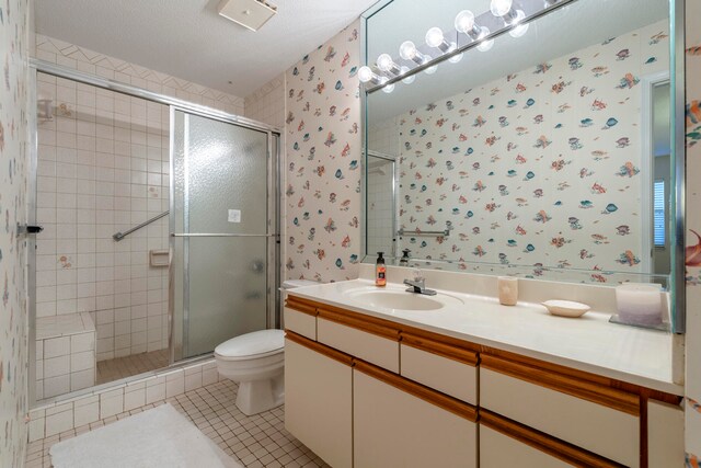 bathroom with large vanity, a shower with shower door, toilet, tile flooring, and a textured ceiling