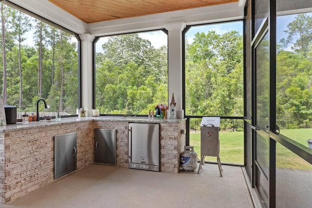 unfurnished sunroom with wooden ceiling, a healthy amount of sunlight, and sink