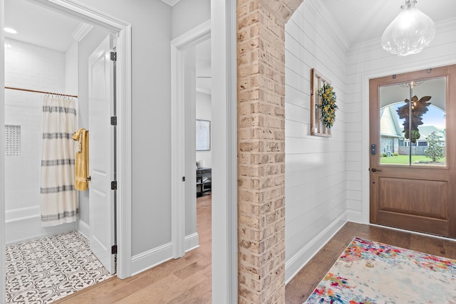 tiled foyer entrance featuring wood walls and crown molding