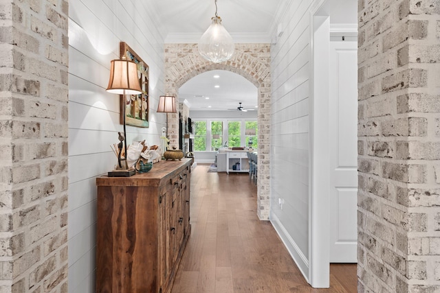 corridor featuring ornamental molding, dark hardwood / wood-style flooring, and brick wall