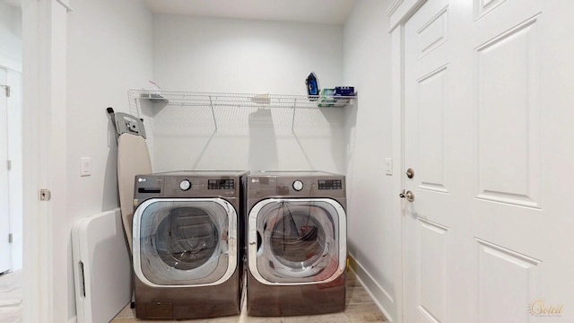 laundry room with washing machine and dryer and light tile floors